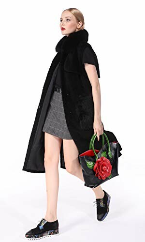 Fashion model in black coat carrying a handbag with a red flower design.