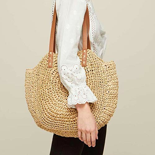 Woman carrying a woven straw tote bag with brown handles