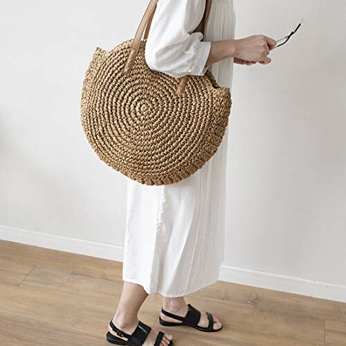 Woman in white dress carrying a large round straw bag.